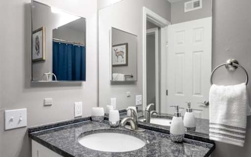 A bathroom with a sink, mirror, and towel.