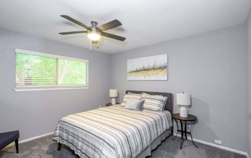 A bedroom with a bed, two lamps, and a painting on the wall.