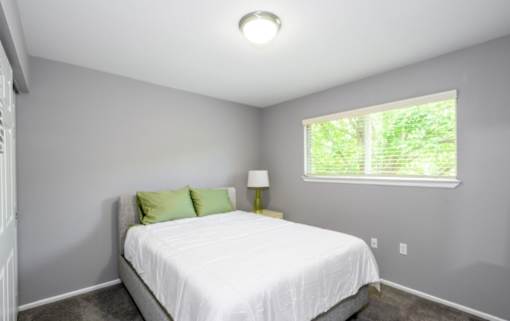 A bedroom with a white bed and green pillows.