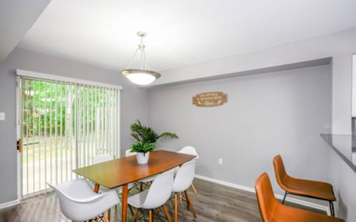 A dining room with a wooden table and white chairs.