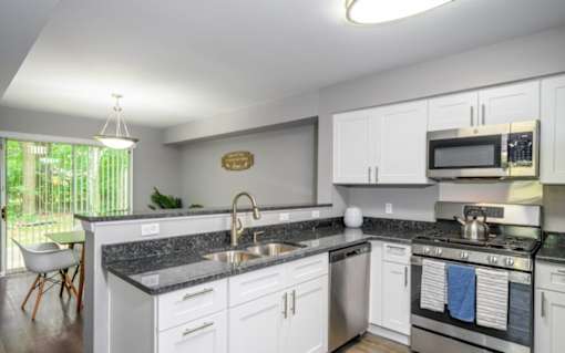 A kitchen with white cabinets and a black countertop.