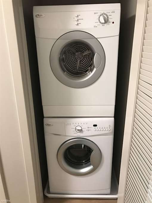 A white washing machine is stacked on top of another white washing machine.