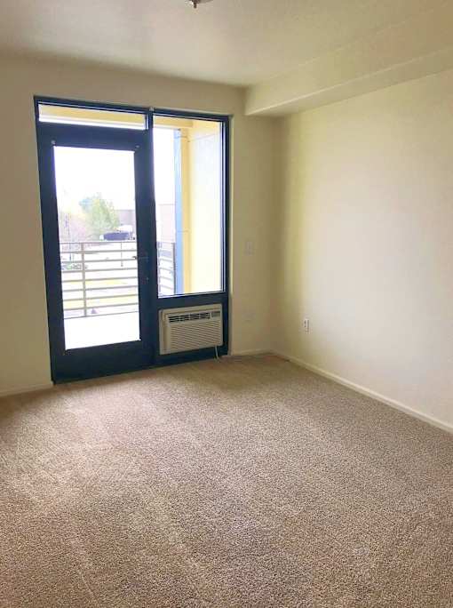 A room with a carpeted floor and a sliding glass door.