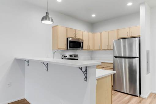 A kitchen with a white counter and a stainless steel refrigerator.