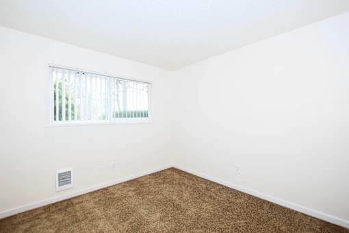 A room with a window and a carpeted floor.