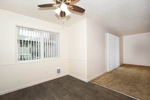 A room with a ceiling fan and a window with blinds.