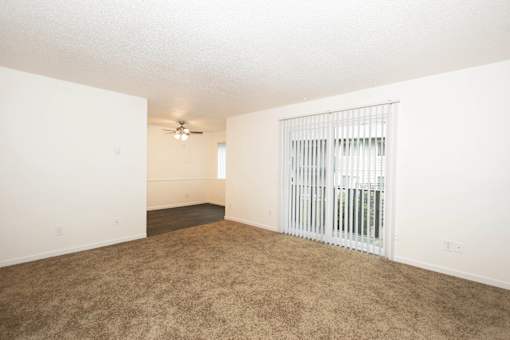 A room with a ceiling fan and a window with blinds.