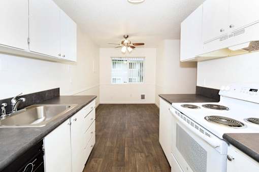 A kitchen with white cabinets and a stove top oven.