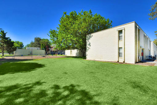 a large yard in front of a white building and a tennis court