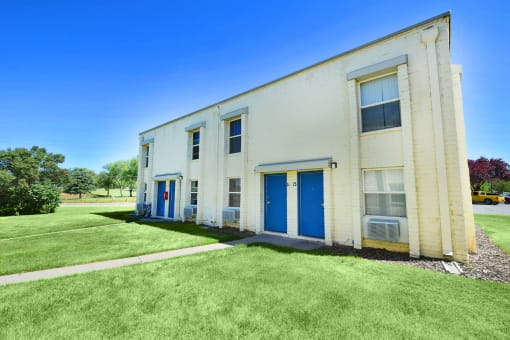 an old white building with blue doors and a lawn