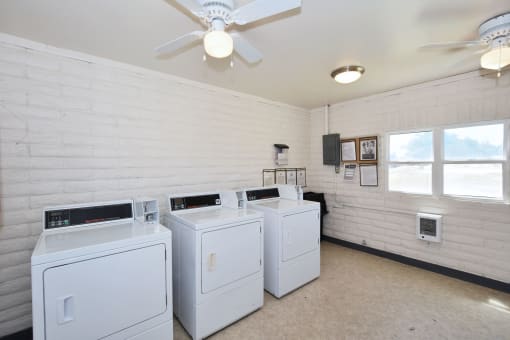 the laundry room has four washers and dryers and a ceiling fan