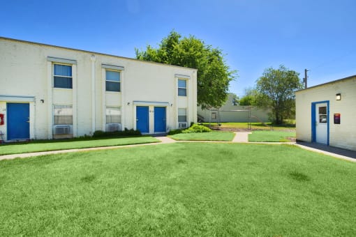 a large white building with blue doors and a lawn