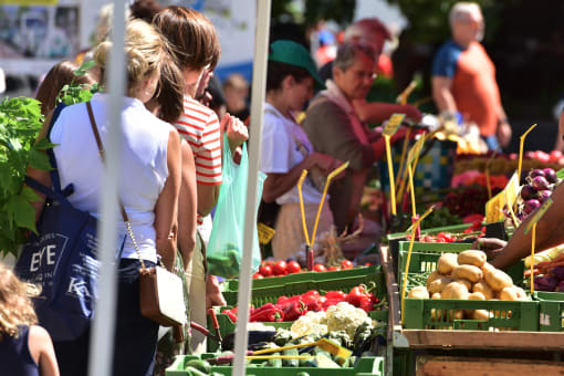 people buying fruits and vegetables at an outdoor market