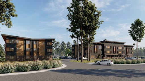A modern building with a curved wooden facade is surrounded by trees and a car is parked in front.