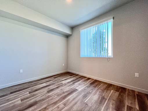 A room with wooden flooring and a window with blinds.