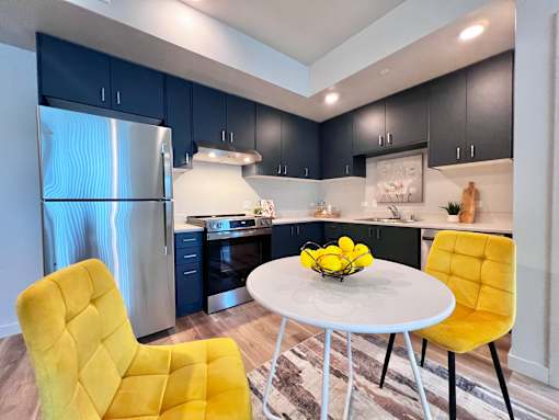 A modern kitchen with a yellow chair and a white table.