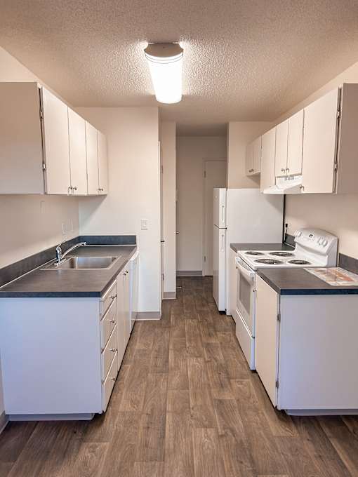A kitchen with white cabinets and a black counter top.