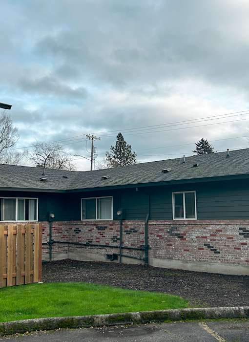 A house with a grey roof and a brick wall.