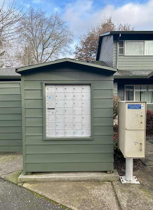 A green shed with a white door and a mailbox on the side.