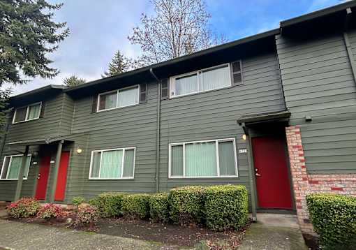 A grey house with red doors and windows.