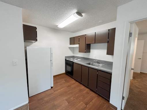 A kitchen with brown cabinets and a white refrigerator.