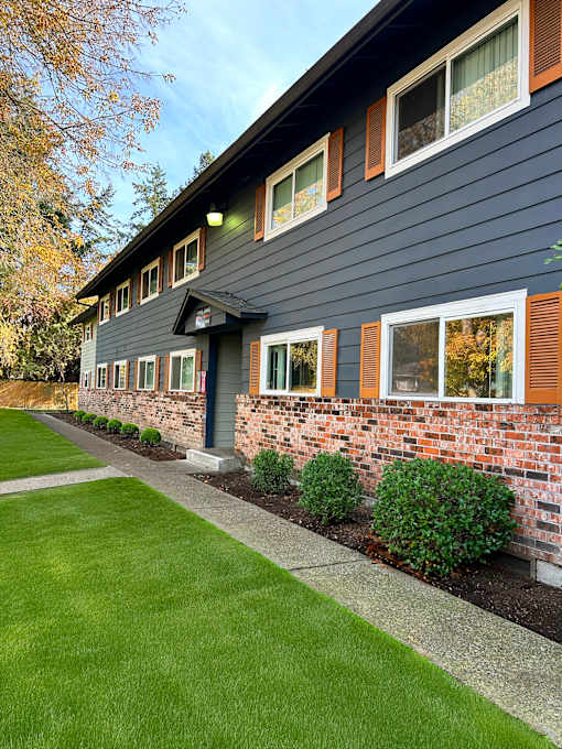 A house with a grey siding and a brick wall.