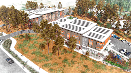 A building with a brown roof and orange walls is surrounded by trees.