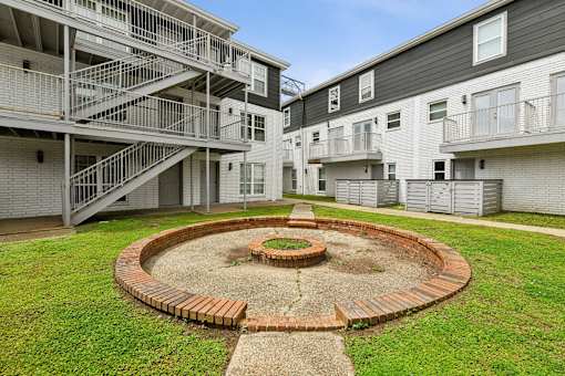 A courtyard with a brick fire pit surrounded by apartment buildings.
