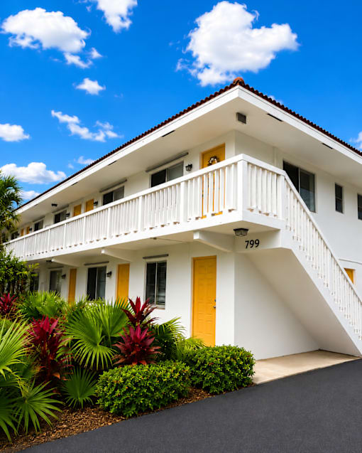 A white house with a yellow door and a balcony.