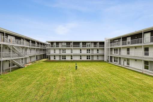 A large grassy courtyard in front of apartment buildings.