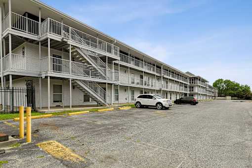 A parking lot in front of a multi-story apartment building.
