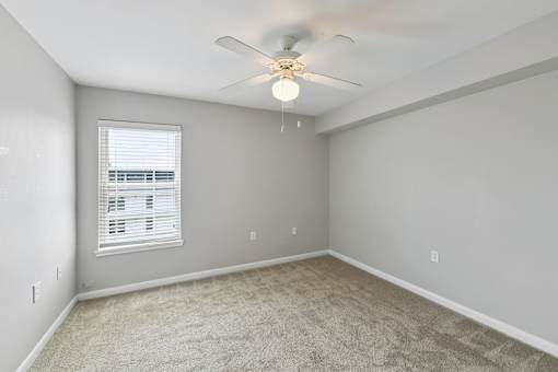 A room with a ceiling fan and carpeted floor.