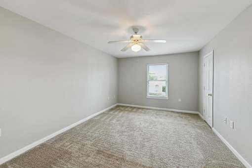 A room with a carpeted floor and a ceiling fan.