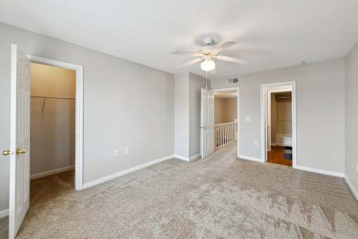 A spacious room with a carpeted floor and a ceiling fan.