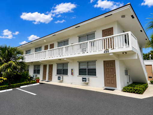 A white two-story house with a balcony on the second floor.