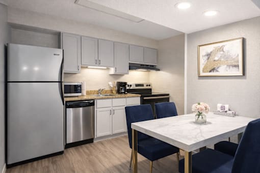 A kitchen with a refrigerator, table, and chairs.