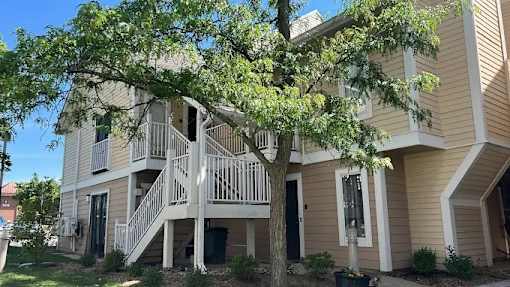 A tree is in front of a two-story apartment building.