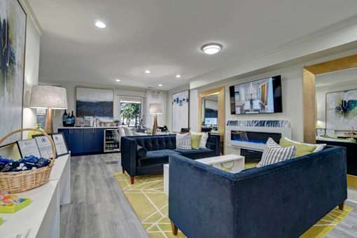 A spacious living room with a dark blue sofa and a yellow rug.