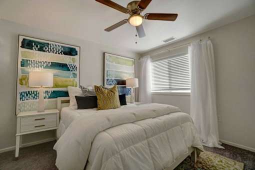 A bedroom with a white bed and a ceiling fan.