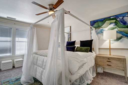 A bedroom with a canopy bed and a ceiling fan.