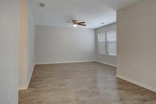 A room with a ceiling fan and wooden flooring.
