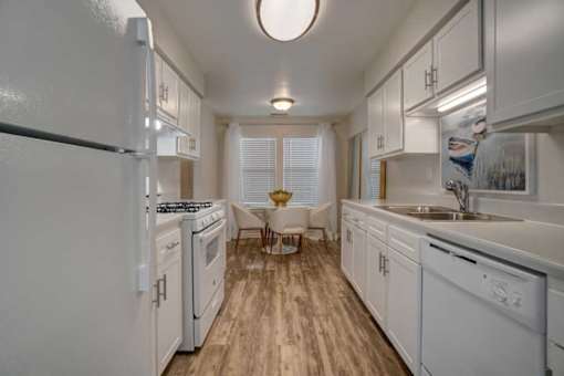 A kitchen with white appliances and wooden floors.