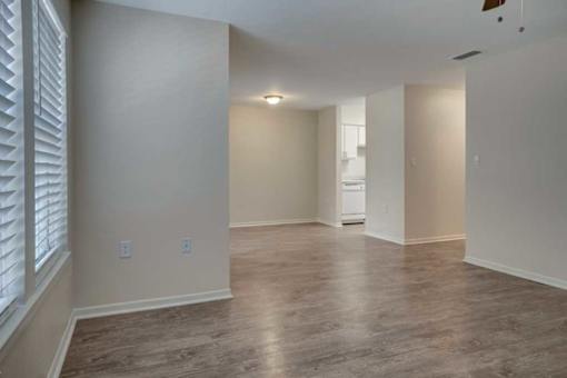A spacious room with wooden flooring and white walls.