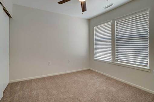 A room with a ceiling fan and carpeted floor.
