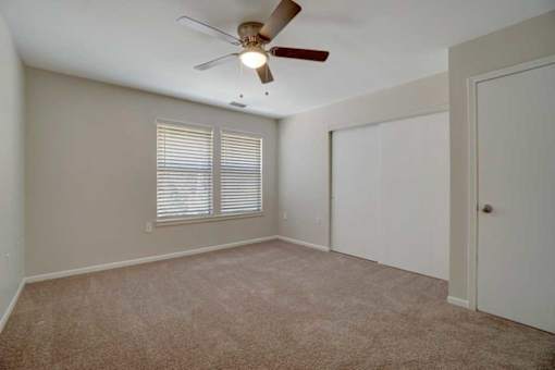 A room with a ceiling fan and carpeted floor.