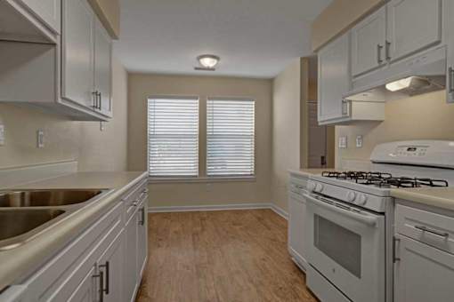 A kitchen with a stove, sink, and cabinets.