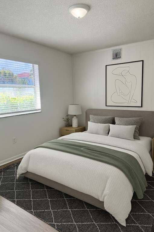 A bedroom with a bed, nightstand, and a framed picture on the wall.