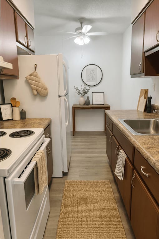 A kitchen with a white stove top oven and white refrigerator.