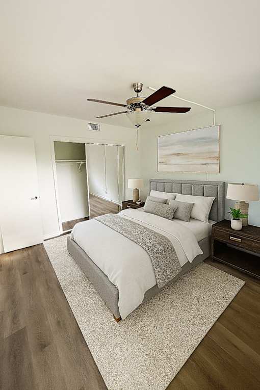 A bedroom with a bed, nightstand, and a ceiling fan.