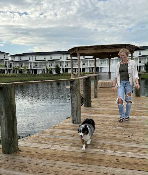 A woman walks her dog on a wooden dock.
